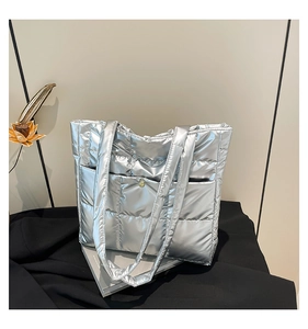 Detail of silver quilted tote bag featuring a front pocket with golden metal snap button