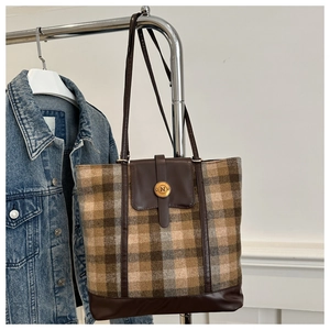 Detail of wool plaid tote bag with brown leather base and vintage N metal buckle