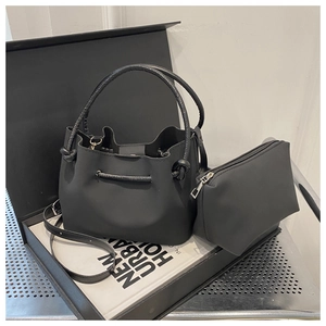 Detail view of black drawstring bucket bag with matching zipper pouch on a gift box