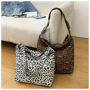 Detail of large leopard print tote bags in brown and white on a light wood floor