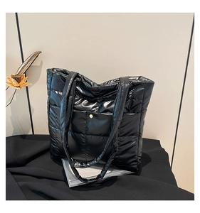 Macro detail of high-shine quilted puffer tote bag with elegant golden button pocket