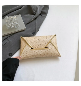 Detail shot of beige ostrich textured envelope clutch with elegant gold metal trim and edges