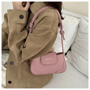 Detail of pink faux leather bag showing knot strap design and fashion logo lettering
