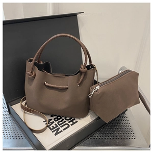 Detail view of dark brown suede bucket bag with round handle and matching zipper pouch