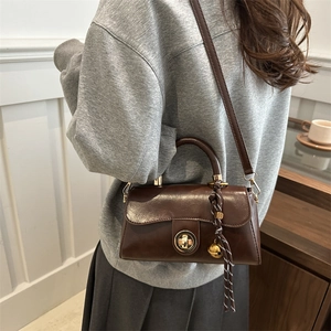 Brown leather crossbody square bag with gold twist lock and woven charm detail