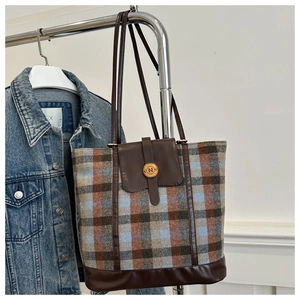 Close-up of vintage plaid wool backpack with leather details and brass button closure