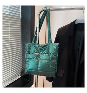 Detail of green quilted tote bag with metallic finish and gold clasp hanging on hanger