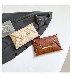 Detail of ostrich-textured envelope clutches with gold metal trim in beige and brown