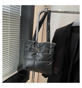 Detail view of black quilted puffer tote bag with glossy finish and metal snap pocket