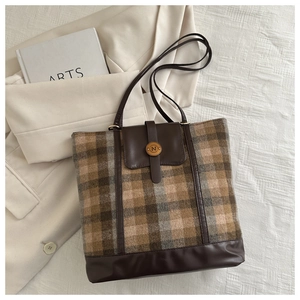 Detail of wool plaid tote bag featuring brown leather trim and golden metal N clasp