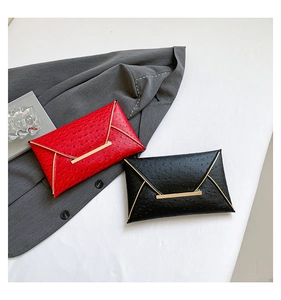 Detail of red and black textured ostrich leather envelope clutches with gold metal bars