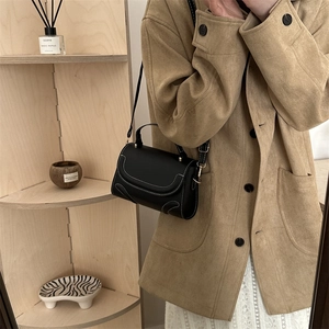 Schicke schwarze Leder-Umhängetasche mit weißen Kontrastnähten an einem Model