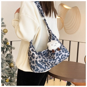 Détail d'un sac à bandoulière hobo à imprimé léopard avec un pendentif nuage en peluche