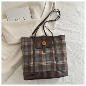 Detailed close-up of vintage wool plaid pattern and leather trim on a tote backpack