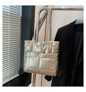 Detail of champagne gold quilted tote bag with metallic texture and circular buckle