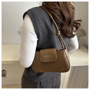 Detail of a brown leather shoulder bag featuring an embossed white text logo on the flap
