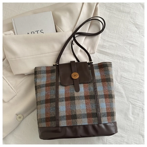 Detailed close-up of a plaid wool backpack with brown leather strap and N-buckle detail