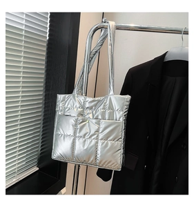 Detail of silver quilted puffer tote bag with metallic finish and soft padded texture
