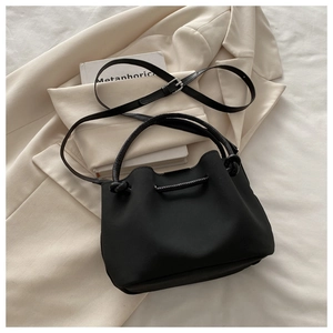Close-up of black pleated drawstring bucket bag featuring knotted handle and leather texture