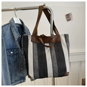 Detail of large striped canvas tote bag showing reinforced leather corners and dual straps