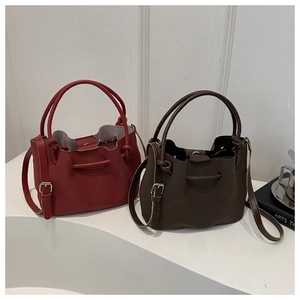 Detail view of red and dark brown pleated bucket bags with handles and adjustable straps