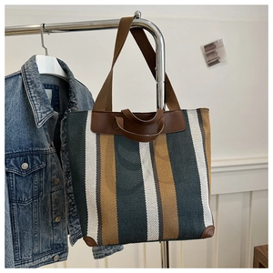 Detail of striped canvas tote bag with leather handles and reinforced corners for daily use