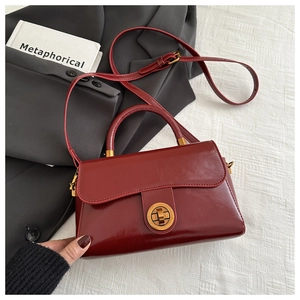 Détail du sac à main vintage bordeaux en cuir ciré avec fermoir rotatif doré brillant