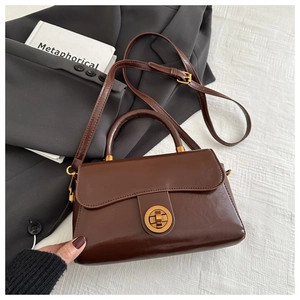 Détail du sac en cuir marron foncé avec fermoir rotatif doré et texture vintage
