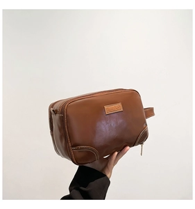 Detail of dark brown leather toiletry bag with double zippers and side handle