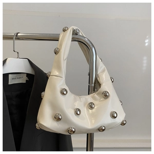Detailed macro view of white glossy faux leather shoulder bag with silver metallic studs