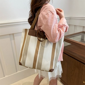 Large striped canvas tote bag with brown leather trim and handles for daily commute