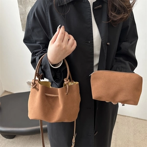 Minimalist brown suede bucket bag with drawstring closure and contrasting yellow lining