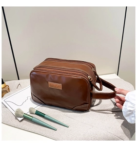Detailed view of brown PU leather toiletry bag with double zippers and top handle