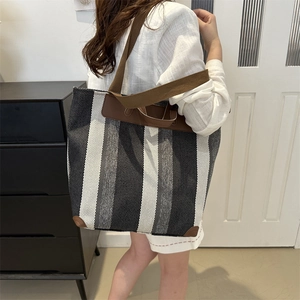 Large capacity striped canvas tote bag with brown handles shown on female model
