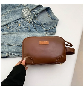 Detail of vintage brown leather handbag featuring contrast white stitching and square logo