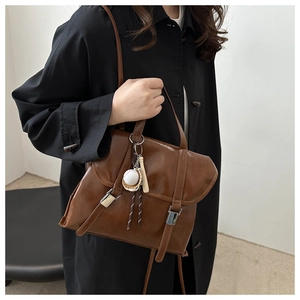 Dettaglio della borsa tote marrone vintage con fibbie retrò e ciondolo baseball