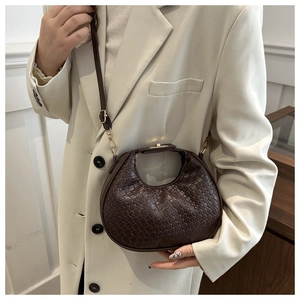 Detail view of a woven dark brown crescent shoulder bag with metallic gold hardware