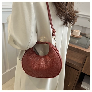 Detail of burgundy crescent bag featuring woven PU texture and golden metal buckle