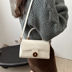 Sac bandoulière blanc crème vintage avec fermoir rotatif en laiton sur un mannequin