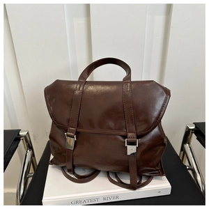 Dettaglio dello zaino vintage in pelle marrone lucida con fibbie argento e patta