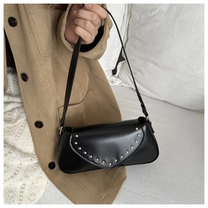 Close-up of vintage black PU shoulder bag with gold rivets and V-shaped flap cover