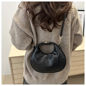 Detailed woven texture of a black crescent crossbody bag shown on a model