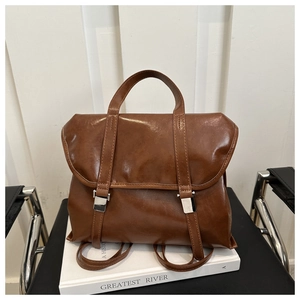 Dettaglio dello zaino vintage in pelle marrone con fibbie argento su sfondo bianco