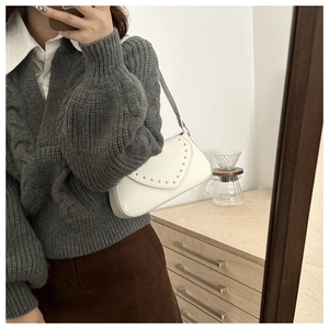 Detail of white PU leather underarm bag with gold studs and V-shaped flap cover
