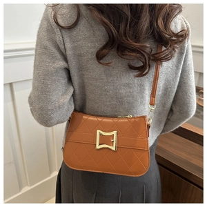 Sac à bandoulière matelassé caramel avec boucle dorée porté par un mannequin