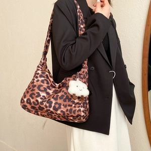 Sac fourre-tout chic à imprimé léopard avec pendentif blanc porté par un modèle