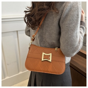 Sac bandoulière marron matelassé avec boucle dorée porté par un mannequin dans un cadre épuré