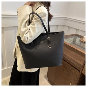 Detail of black leather tote bag featuring gold hardware and logo for daily office commute