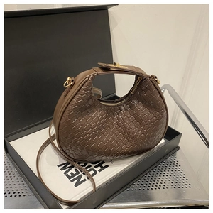 Detailed view of woven brown leather hobo bag with gold hardware in a gift box setup