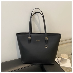 Vue détaillée d'un sac cabas noir avec logo doré posé sur un canapé en cuir luxueux